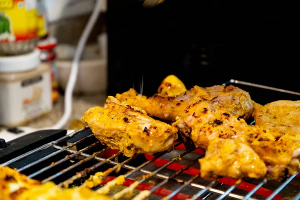 Parrilla de pollo sobre una parrilla eléctrica caliente con barras calientes en casa barbacoa — Foto de Stock