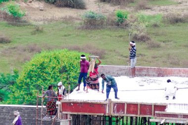 İnşaatın çatısının temelinde betonu karıştırarak ve bir insan zinciri kullanarak çatıya çıkarılarak zavallı bir yoksulluk içindeki işçinin döktüğü yere taşınması.