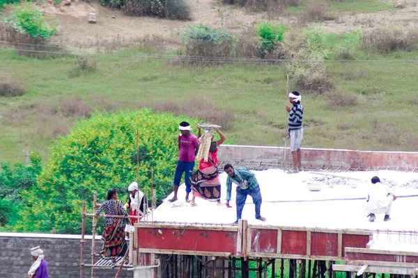 İnşaatın çatısının temelinde betonu karıştırarak ve bir insan zinciri kullanarak çatıya çıkarılarak zavallı bir yoksulluk içindeki işçinin döktüğü yere taşınması.