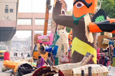 Yoğun bir caddenin kenarında, Ravana 'nın heykelcikleri üzerinde çalışan yaşlı, pasaklı bir kadının düşük pozu.