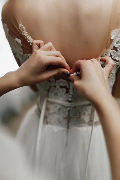 伴娘在新娘的婚纱上按下纽扣 — 图库照片