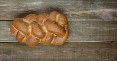 Lezzetli taze beyaz ekmek gevrek altın kabuk kahverengi ahşap bir masa üzerinde ile örgülü.