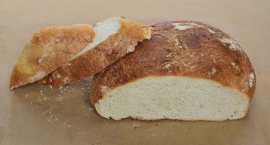 Closeup taze eve yarım bir somun ekmek ve ondan kesilmiş ekmek pişirme, taze ekmek kırıntısı için parşömen üzerine önsezi