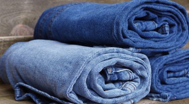 üç çift ahşap arka plan üzerinde katlanmış kot pantolon closeup. seçici odak. kot kavramı. kot moda. Gençler moda.