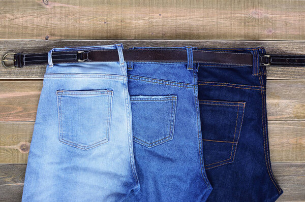 team building. family. three pairs of high waist jeans are connected together by one strap on brown wooden background