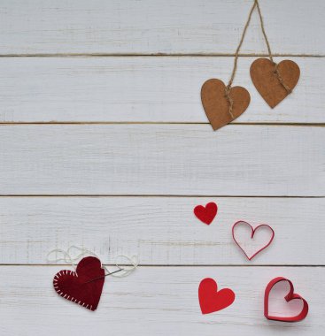 Sevgililer yapma. 14 Şubat kavramı. İki ahşap kalp dize ile bağlı ve kırmızı kalpler ve bir kalp bir sürü yarım kalmış üzerinde beyaz vintage ahşap arka plan bitirmek. Metin için yer.