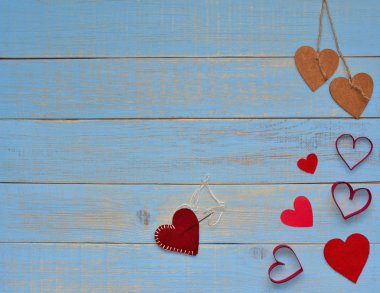 Sevgililer. 14 Şubat kavramı. İki ahşap kalp dize ile bağlı ve kırmızı kalpler ve bir kalp bir sürü yarım kalmış üzerinde mavi vintage ahşap arka plan bitirmek. Metin için yer.