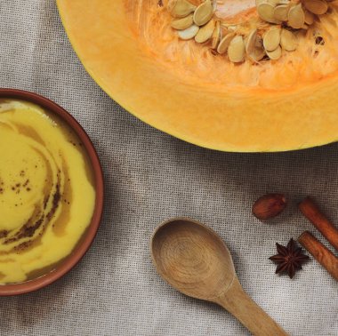 keten kumaş, tohumları kabak kabak püresi çorba vejetaryen, sağlıklı kavramı, bir kil tabak, baharat (Tarçın biftek, bir Yıldız anason ve bütün Hindistan cevizi), tahta kaşık için üstten görünüm yatıyordu 