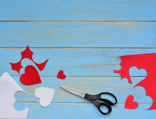 Sevgililer ev yapımı. 14 Şubat kavramı. Sevgililer büyük makas ve kırmızı ve beyaz ile dekoratif yapma süreci üzerinde mavi vintage ahşap arka plan hissettim. Metin için yer.