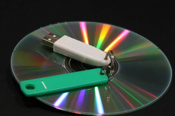 CD with color beams and electronic key on a dark background