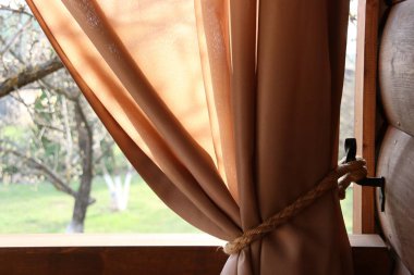 Bej perdeler ve ip kancaile Veranda. Metal kancalarda halat kancaları