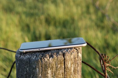 Yeşil çim arka planda eski ahşap sonrası siyah akıllı telefon