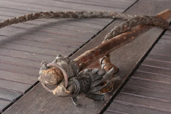Old braided leather whip with a wooden handle on a wooden wall