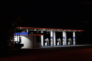 Yol kenarındaki benzin istasyonunda kara gece gökyüzüne karşı