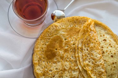 Rusya, Severodvinsk, bir bardak çay, dokulu beyaz bir arka plan üzerinde ev yapımı Rus krep yığınıyla lay düz