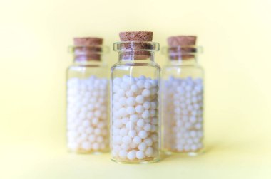 Canlarda homeopatik hazırlıklar. Sarı arka plan üzerinde şişelerde kimyasallar olmadan Homeopatik doğal ilaçlar. Alternatif homeopati ilaç otlar, sağlık ve hap kavramı