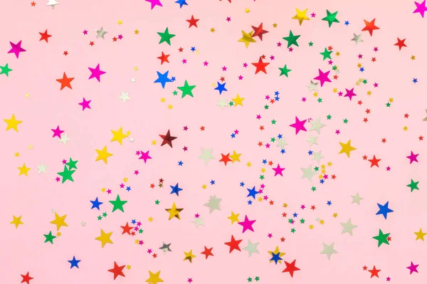 Estrelas multicoloridas brilham no fundo rosa. Férias festivas pano de fundo pastel. Conceito de celebração. Vista superior, deitado plano. Horizontal — Fotografia de Stock
