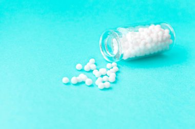 Nane arka plan üzerinde cam şişe homeopatik globüller. Globüller şişeden saçılmış. Alternatif homeopati ilaç otlar, sağlık ve hap kavramı. Seçici odaklama