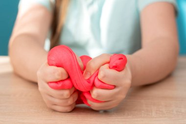 Çocuk elinde pembe balçığı ezer ve buruşturur. El yapımı balçık denen bir oyuncak. Çocuklar bilim deneyiyle eğleniyor ve yaratıcı oluyorlar..