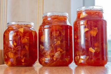 Mutfak arka planında farklı boyutlarda cam kavanozlarda elma reçeli. Çevre ürünleri ve yaz meyveleri hasadı kavramı. Yakın plan..