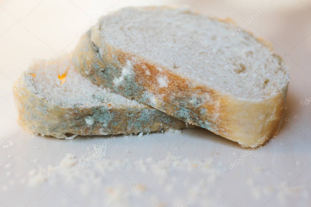 Slices of moldy bread on light background, concept of unsuitable food