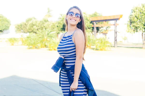 Portrait of a happy girl. She is wearing sunglasses and tying the blouse at the waist. Photo of Brazil. Concept of lifestyle. Style blogger, tourist visiting a themed square — Stock Photo, Image