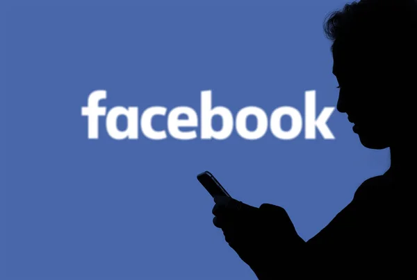 27 juni 2019, Brazilië. In deze foto illustratie silhouet van een persoon die naar de smartphone met het Facebook-logo op de achtergrond — Stockfoto