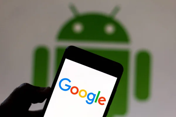 9 июля 2019 года, Бразилия. На этой фотографии логотип Google отображается на смартфоне. На заднем плане логотип Android — стоковое фото