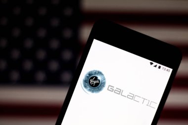 9 Temmuz 2019, Brezilya. Bu fotoğraf illüstrasyonunda Virgin Galactic logosu bir akıllı telefonda görüntülenir. Arka planda, Amerika Birleşik Devletleri bayrağı