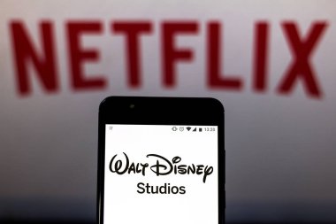 16 Ağustos 2019, Brezilya. Bu fotoğraf illüstrasyonWalt Disney Studios logosu bulanık arka plan üzerinde bir akıllı telefon ve logo Netflix görüntülenir