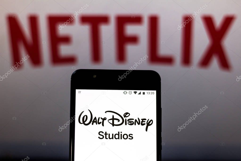 August 16, 2019, Brazil. In this photo illustration The Walt Disney Studios logo is displayed on a smartphone and logo Netflix on the blurred background.