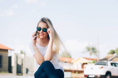 Onun akıllı telefon kullanarak Modern genç kadın - Genç şık hipster onu güneş gözlüğü ile kaygısız gülümseyen ve telefonda arkadaşları ile konuşurken. Moda, moda ya da bin yıllık nesil konsepti