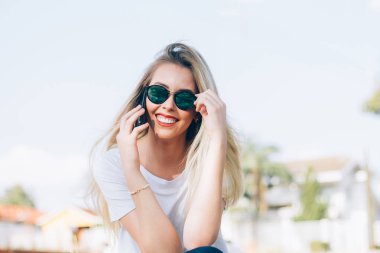 Onun akıllı telefon kullanarak Modern genç kadın - Genç şık hipster onu güneş gözlüğü ile kaygısız gülümseyen ve telefonda arkadaşları ile konuşurken. Moda, moda ya da bin yıllık nesil konsepti