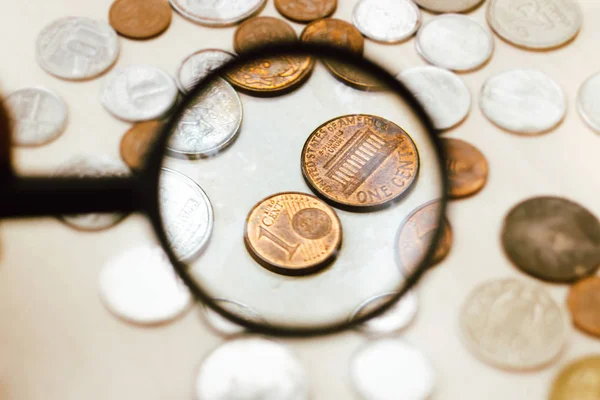 Κέρμα του ενός λεπτού του ευρώ, το οποίο απεικονίζεται μέσα από μεγεθυντικό φακό - κέρματα στο τραπέζι - έννοια της οικονομίας και της χρηματοδότησης. — Φωτογραφία Αρχείου