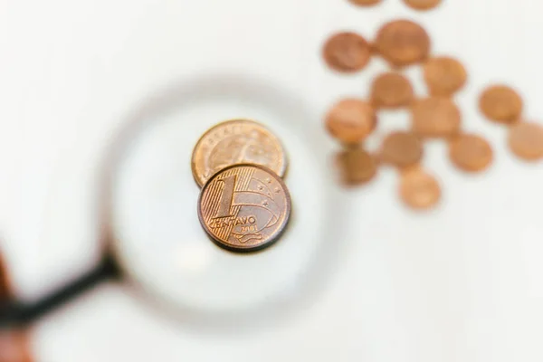 Echte Ein-Cent-Münze unter der Lupe - Münzen auf dem Tisch - Wirtschafts- und Finanzkonzept. — Stockfoto