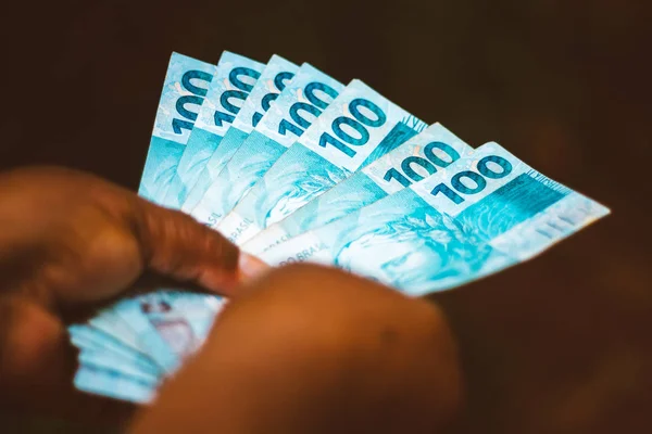 Mano de una mujer negra mostrando dinero brasileño - Cien billetes de banco reales brasileños - Concepto de economía - inflación y negocios . — Foto de Stock