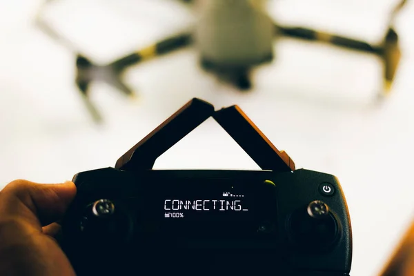 Drone pilot holds remote control with inscription plugging in display - Antennas of control are crossed — Stock Photo, Image