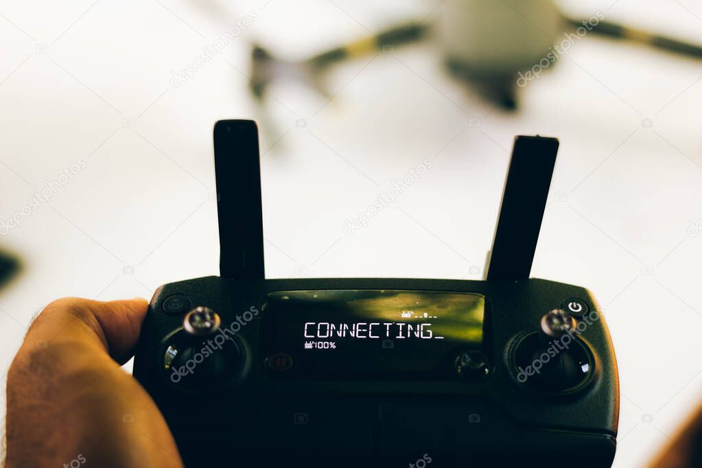 Drone pilot holds remote control with inscription plugging in display - Antennas of control are raised