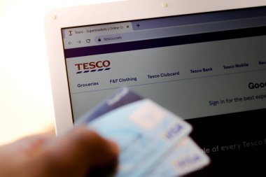 5 Temmuz 20020, Brezilya. Tesco web sitesi arka planda bir dizüstü bilgisayarda gösteriliyor ve bir kişi banka kartı tutuyor