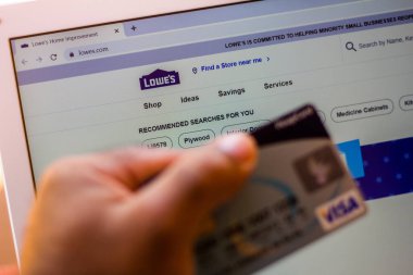 5 Temmuz 20020, Brezilya. Lowes Şirketleri 'nin web sitesi arka planda dizüstü bilgisayarda gösteriliyor ve bir kişi banka kartı tutuyor.