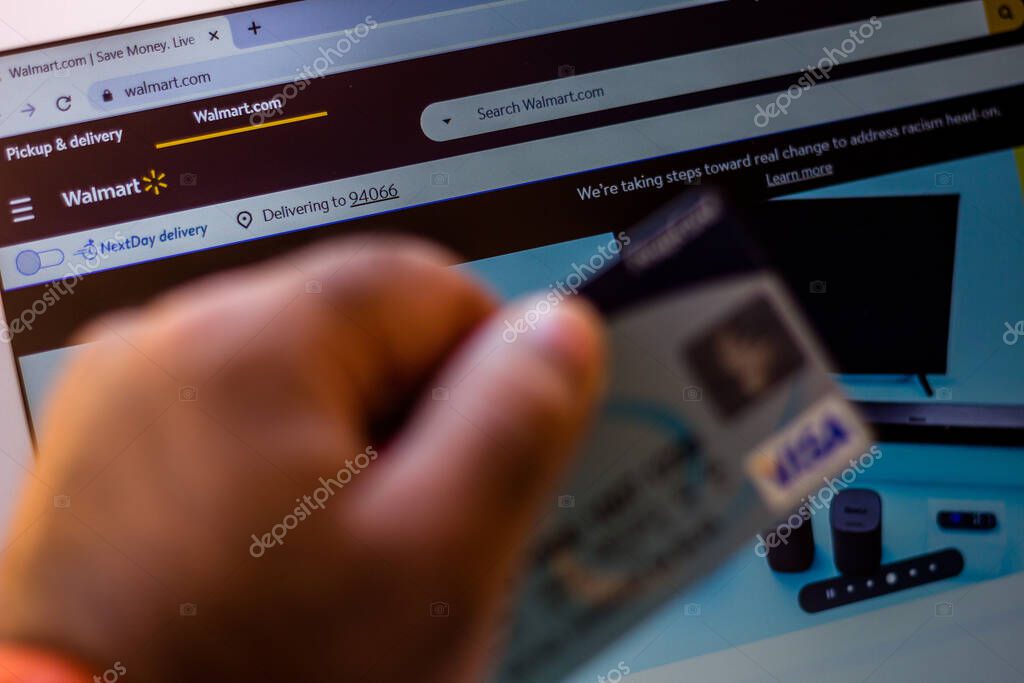 July 5, 20020, Brazil. The Walmart website is shown on a laptop in the background and a person holds a bank card