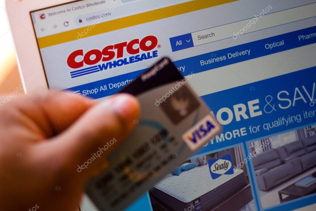 July 5, 20020, Brazil. The Costco Wholesale Corporation website is shown on a laptop in the background and a person holds a bank card
