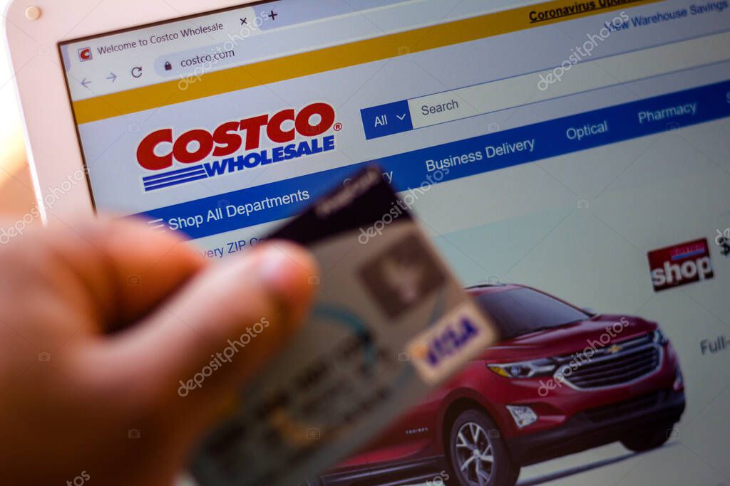 July 5, 20020, Brazil. The Costco Wholesale Corporation website is shown on a laptop in the background and a person holds a bank card