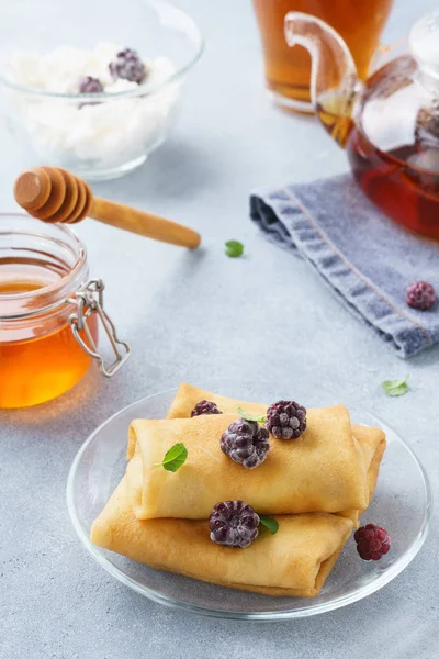 Ricotta blintzes. Stuffed crepes served with honey and blackberries.