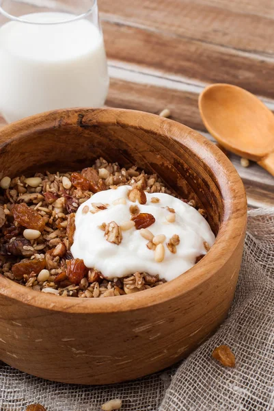 Домашняя мюсли с орехами, изюмом и йогуртом в деревянной миске — стоковое фото