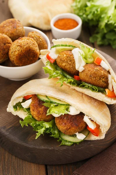 Falafel and fresh vegetables in pita bread with sauce. — Stock Photo, Image