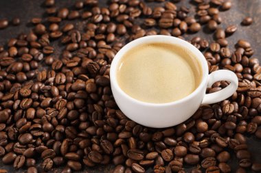 Kahve fincanı kavrulmuş kahve çekirdeği üzerinde. Sıcak güneş ışığı.