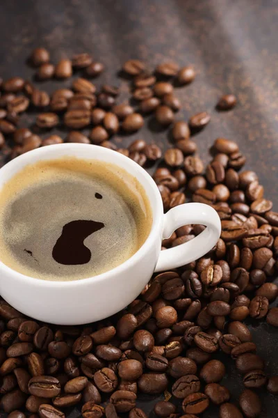 Xícara de café em grãos de café torrados. Fundo escuro, raios de sol . — Fotografia de Stock