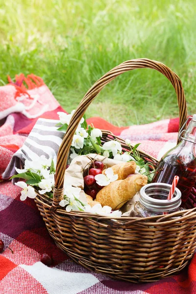 Keranjang piknik dengan makanan. Croissant, cherry berry dan jus . — Stok Foto