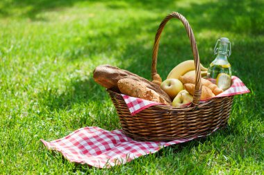 Piknik sepeti, parkta yiyecek ve içeceklerle dolu..
